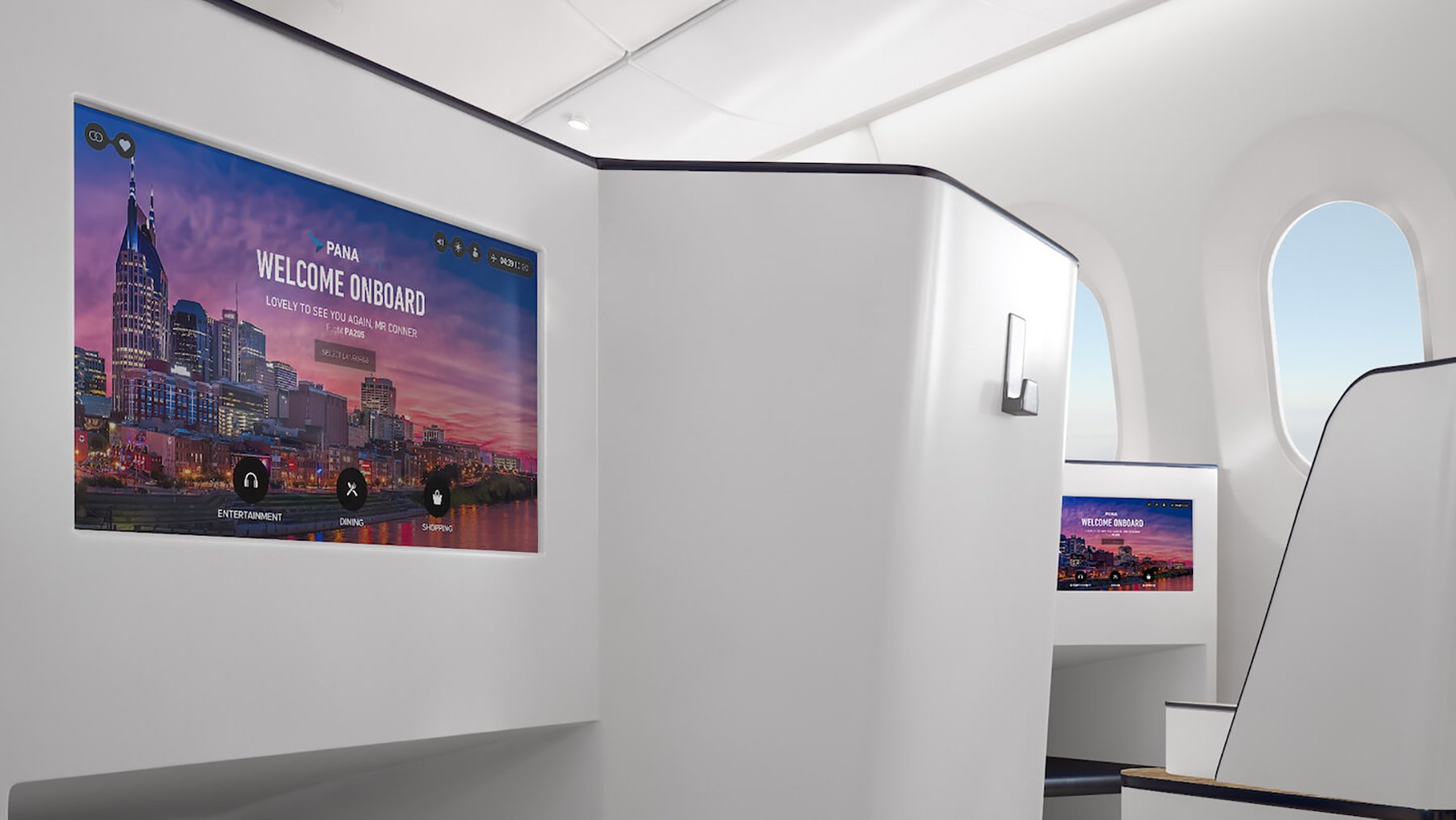 Interior of a premium aircraft cabin with individual suites and large screens displaying a welcome message